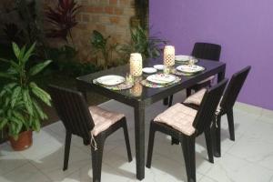 Una mesa negra con cuatro sillas y velas. en Casa Hospedaje Aromas, en Tarapoto