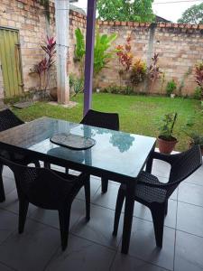una mesa de cristal y sillas en un patio en Casa Hospedaje Aromas en Tarapoto