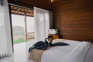 two swans sitting on a bed in a bedroom with a window at The Akasea Villa Bali in Ungasan