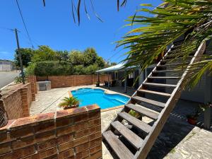 a swimming pool with a wooden staircase next to a house at Bas de villa Noumea in Noumea