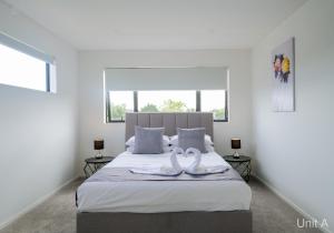 - 2 serviettes de toilette en cygne sur un lit dans une chambre dans l'établissement Modern Howick Town House Fibre WiFi Netflix, à Auckland