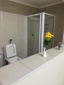 La salle de bains est pourvue de toilettes et d'un vase avec des fleurs jaunes. dans l'établissement Triple T Guest house, à Johannesbourg