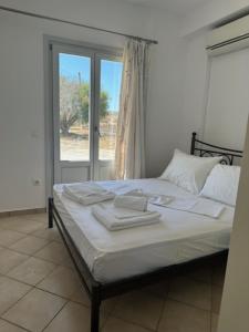 een slaapkamer met een bed met witte lakens en een raam bij IFESTIA HOUSE in Agia Paraskevi