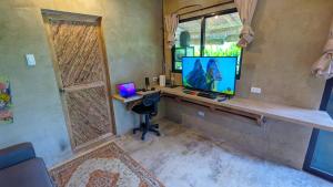 a room with a desk with a laptop and a television at Tropical Haven with Dedicated Office Space in Siargao in General Luna