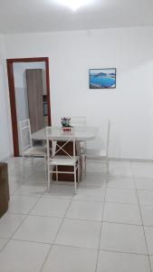 a dining room with a white table and chairs at Jockey Family_Suave in Vila Velha