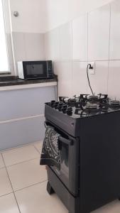 a black stove in a kitchen with a microwave at Jockey Family_Suave in Vila Velha
