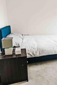 a bed with a wooden table and a blue chair at 2bed Central Apartment + Gym + Pool in London