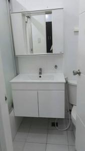 a white bathroom with a sink and a mirror at White House near Thunderbird Resort in Parian