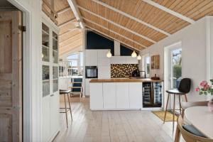 a kitchen with white cabinets and a wooden ceiling at Summer House With Sauna Near Flle Strand, in Rønde