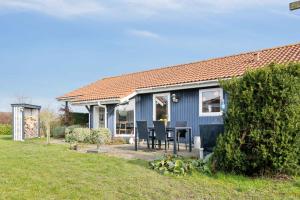 a blue house with a table in a yard at Summer House With Sauna Near Flle Strand, in Rønde