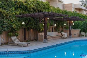 basen z drewnianą pergolą i krzesłem obok basenu w obiekcie Villa 13 Luxury suites w Kairze