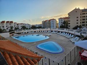 a view of a swimming pool with chairs and a building at DThe heights in Los Cristianos