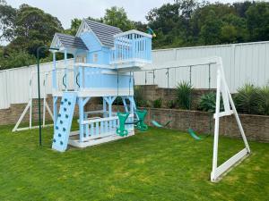 un parque infantil con una casa azul y un tobogán en HEATed Pool, Lake & Beach, Luxury 5 B/R House, en Lake Illawarra