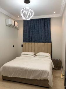 um quarto com uma grande cama branca e um lustre em Distinctive chalet in Dur.Marina em Durat Alarous