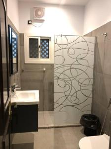 uma casa de banho com um chuveiro, um lavatório e um espelho. em Distinctive chalet in Dur.Marina em Durat Alarous