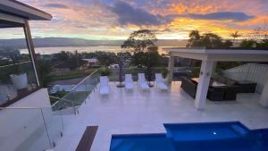 uma vista a partir da varanda de uma casa com um pôr-do-sol em HEATed Pool, Lake & Beach, Luxury 5 B/R House em Lake Illawarra