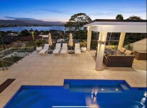 a swimming pool on a patio with a view of the water at HEATed Pool, Lake & Beach, Luxury 5 B/R House in Lake Illawarra