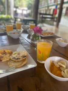 a wooden table topped with a plate of food and orange juice at Hostal Luz de Luna in Palomino