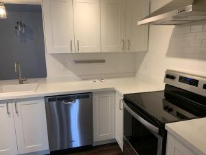 a kitchen with white cabinets and a stainless steel dishwasher at Great family choice in Whitby