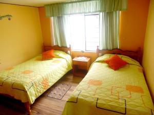 1 Schlafzimmer mit 2 Betten und einem Fenster in der Unterkunft Hostal Rincón Del Turista in Otavalo