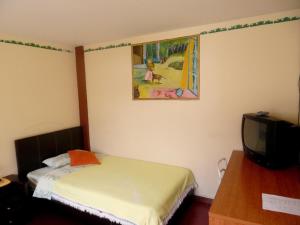a small bedroom with a bed and a tv at Hostal Rincón Del Turista in Otavalo