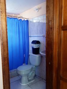 baño con aseo y cortina de ducha azul en Hostal Rincón Del Turista, en Otavalo