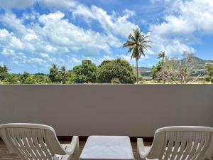 two chairs on a balcony with a view of a palm tree at idyllic apartment in Chaweng