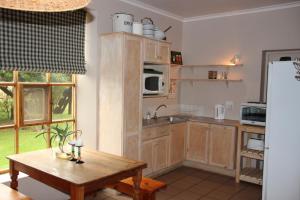 a kitchen with wooden cabinets and a table and a refrigerator at Potteberg Guest Farm in Malgas