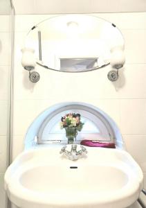 uma casa de banho com um lavatório com um vaso de flores em Katharinenhof App Marsch em Tönning