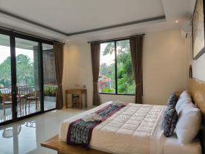 a bedroom with a large bed and large windows at Pondok Bambu Homestay in Ubud