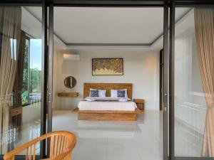 a bedroom with a bed and a sliding glass door at Pondok Bambu Homestay in Ubud