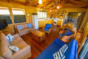 a living room with blue furniture and a kitchen at Bimbimbi - Holiday hideaway by the bay of 1770 in Seventeen Seventy