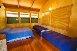 two beds in a room with wooden floors at Bimbimbi - Holiday hideaway by the bay of 1770 in Seventeen Seventy