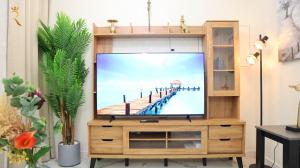 TV en un centro de entretenimiento de madera en una sala de estar en Chalet 2BR Duplex Apartment en Abu Dabi