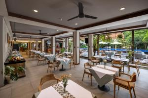 a restaurant with tables and chairs and windows at Taksu Sanur Hotel in Sanur