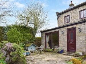 a stone house with a red door and a patio at Mitsys Cottage in Darley
