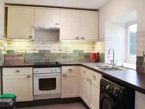 a kitchen with white cabinets and a sink at Mitsys Cottage in Darley