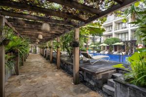 a pergola next to a swimming pool with a chair at Taksu Sanur Hotel in Sanur