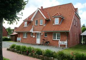 ein rotes Backsteinhaus mit einem Schild davor in der Unterkunft Haus Theo Luise Whg 03 in Sankt Peter-Ording