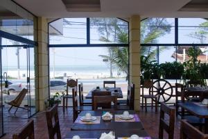 een restaurant met tafels en stoelen en uitzicht op het strand bij Hotel Bellatrix in Macaé