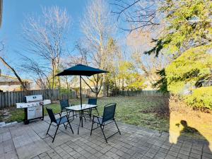 a patio with a table and chairs and an umbrella at Lake Simicoe town cottage near Innisfil Beach Park in Innisfil