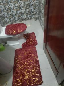 a bathroom with a toilet and a rug on the floor at Biba Stay in Dakar