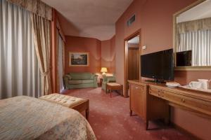 a hotel room with a bed and a flat screen tv at Borgo Palace Hotel in Sansepolcro