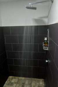 a bathroom with black tiles and a shower at Epimoni in Poás
