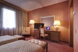a hotel room with two beds and a television at Borgo Palace Hotel in Sansepolcro