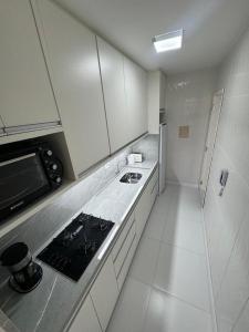 Il comprend une cuisine blanche équipée d'une cuisinière et d'un réfrigérateur. dans l'établissement Amplio apartamento a cuadra del mar, cerca de todo, à Balneário Camboriú