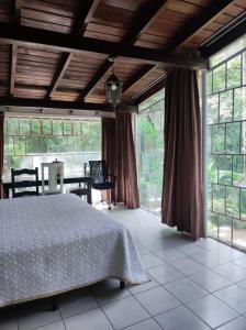 um quarto com uma cama e janelas grandes em VILLA ELENA un refugio en el bosque em El Manzanillo
