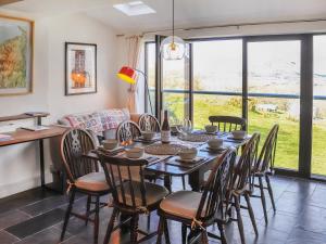 uma sala de jantar com uma mesa longa e cadeiras em Bron Madog em Minffordd