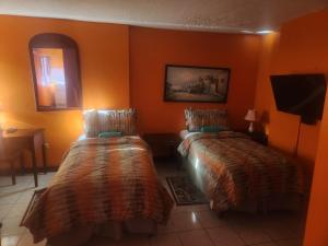 2 camas en una habitación con paredes de color naranja en Turtle Towers, en Ocho Ríos