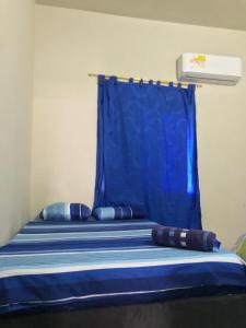 een bed met een blauw gordijn en kussens erop bij Hotel 7 in Cúcuta